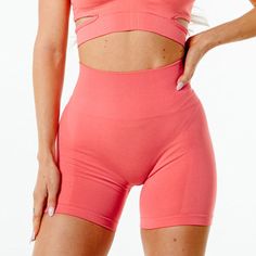 a woman wearing pink shorts and a cropped top with cutouts on the sides