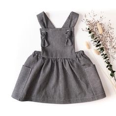 a black and white striped dress next to some dried flowers on a white background with one flower in the foreground