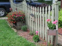 a wooden fence with flowers growing on it and a truck parked in the background behind it