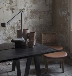 a black table with two brown chairs and a lamp on it in front of a brick wall