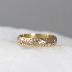 a gold wedding ring sitting on top of a white surface