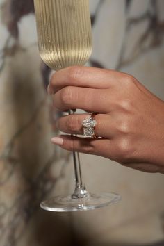 a person holding a wine glass with a diamond ring on it