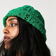 a woman wearing a green crochet hat with her hair blowing in the wind