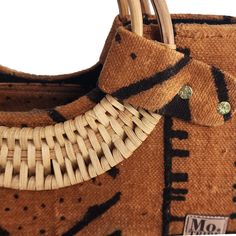 Introducing the Nasika Tote, a stunning handbag crafted from rich mudcloth. This traditional Malian fabric is renowned for its unique texture and cultural significance, making each bag a wearable piece of art. The intricate patterns and earthy tones of the mudcloth create a sophisticated look that's both elegant and eye-catching. With its spacious interior, sturdy cane handles, and inner pocket, this bag is as functional as it is beautiful. Every purchase supports women from low-income weaving c Brown Handwoven Top Handle Bag, Brown Woven Bags As Gifts, Brown Woven Bags For Gifts, Eco-friendly Brown Bag With Bamboo Handle, Eco-friendly Brown Shoulder Bag With Top Carry Handle, Brown Shoulder Bag With Bamboo Handle For Daily Use, Everyday Brown Shoulder Bag With Bamboo Handle, Brown Jute Bag With Bamboo Handle, Traditional Bag With Bamboo Handle In Natural Color