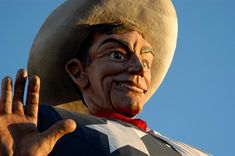 a statue of a man wearing a cowboy hat and holding his hand up in the air