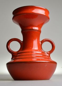 a red vase sitting on top of a white table