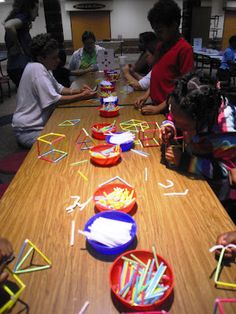 children are sitting at a long table with plastic straws