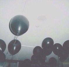 several black balloons are floating in the air