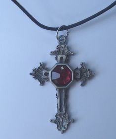 This is a beautiful hand crafted genuine pewter cross necklace. The center of the cross is a genuine red colored faceted Swarovski crystal. The necklace comes on a black cord.The cross is approximately 2 3/4" long and 1 3/4" wide. The cross comes packaged in a gift box. Adjustable Red Cross Necklace, Red Adjustable Cross Necklace, Red Cross Pendant Necklace Gift, Red Cross Pendant Necklace For Gift, Red Spiritual Cross Pendant Jewelry, Red Crucifix Cross Necklace Gift, Red Crucifix Cross Necklace For Gift, Red Gothic Cross Necklace, Adjustable Gothic Cross Pendant Jewelry