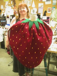 a woman standing in front of a large strawberry shaped bag on top of a chair