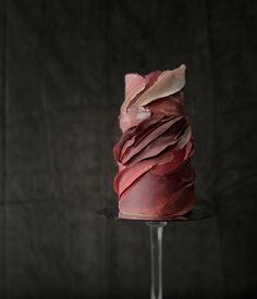 a red cake sitting on top of a glass plate covered in icing and pink frosting