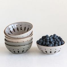 four bowls with blueberries in them sitting next to each other on a white surface