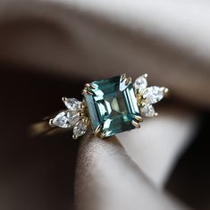 a close up of a ring with an emerald colored stone and white diamonds on it