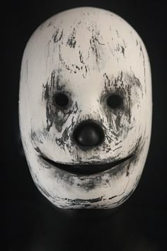 a white mask with a smiley face on it's face and black eyes is shown