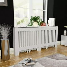 a white radiator sitting on top of a wooden floor next to a window