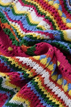 a multicolored crocheted blanket laying on top of a bed