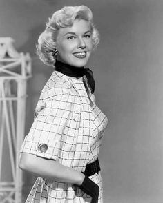 an old black and white photo of a woman in a plaid dress with her hands on her hips