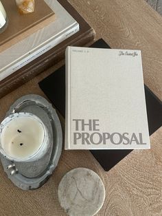 a book sitting on top of a wooden table next to a candle and some doughnuts