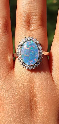 a woman's hand with an opal and diamond ring on top of it