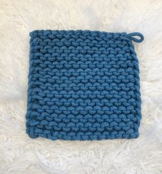 a blue crocheted dishcloth on white fur