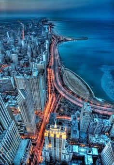 an aerial view of a city at night with the ocean in the backgroud