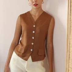 Vintage handmade statement vest blouse in a chocolate brown shade. V neckline and delicate flower-shaped mother of pearl button up fastening. Tailored fit with a slightly cinched waistline to hug beautiful your figure. Decorative front pockets. Lightweight and soft against the body.  You can wear it both as a blouse or layered with a top underneath. It's the perfect garment for a standout look from day to night! BRAND: No tag, handmade MATERIAL: No tag, estimated as viscose **CONDITION: Excellen Chic Brown Tops For Daywear, Elegant Brown V-neck Blouse, Brown V-neck Vest For Workwear, Brown V-neck Vest For Work, Vintage V-neck Tops For Workwear, Brown Tops With Button Closure For Daywear, Elegant Brown V-neck Vest, Classic Brown Tops For Daywear, Brown Workwear Vest With Buttons