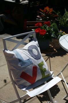 a chair with a pillow sitting on top of it next to a table and flowers