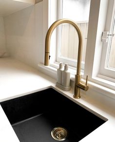 a black sink sitting under a window next to a faucet