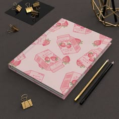 a pink notebook with strawberries and strawberrys on it, surrounded by other items