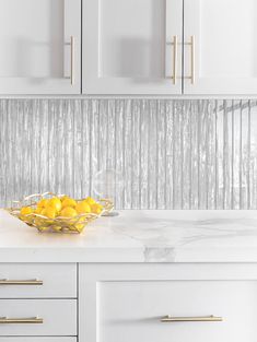 a bowl filled with lemons on top of a kitchen counter