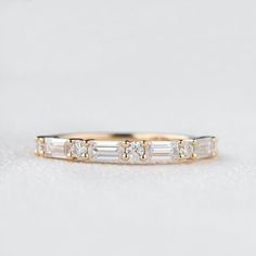 a gold ring with three baguettes and four diamonds on it, sitting on a white surface