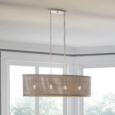 a chandelier hanging from the ceiling in a living room with windows and curtains