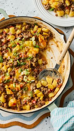 a skillet filled with food on top of a table next to plates and utensils