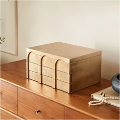 a wooden box sitting on top of a dresser next to a phone and other items