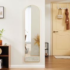 a mirror on the wall in front of a wooden table and shelf with potted plants