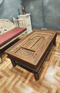 a wooden table sitting on top of a hard wood floor next to a white bench