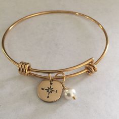 "This listing includes a gold plated stainless steel expandable bangle bracelet with a 1/2\" nu gold discs hand stamped with a compass paired with a Swarovski white pearl. Nu-gold is a copper alloy consisting of 85% copper and 15% zinc. It has a rich warm color and if highly polished resembles gold. This is also known as jewelers brass and will tarnish and need to be polished. What I would like you to know: All of my pieces are hand stamped and made with love just for you. They will arrive in a Gold Stainless Steel Jewelry For Wedding, Adjustable Matte Gold Stainless Steel Jewelry, Matte Gold Adjustable Bangle Jewelry, Adjustable Yellow Gold Stainless Steel Bangle, Matte Gold Bangle Bracelet Gift, Matte Gold Bangle Jewelry For Gift, Gold Charm Bracelet With Extender For Friendship, Adjustable Gold Charm Bracelet For Wedding, Gold Charm Bracelet For Friendship