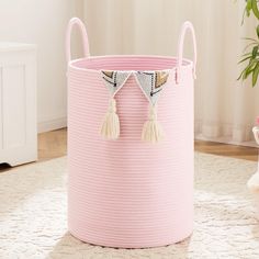 a pink storage basket with tassels on the handles