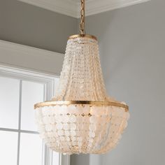 a chandelier hanging from the ceiling in a room with white walls and windows