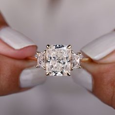 a woman's hands holding an engagement ring with three stone diamonds on the band