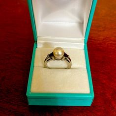 Vintage 14kt White Gold And Pearl Ring. This Is Stamped 14k And Is Real Gold. The Ring Has A Large Center Pearl And Each Side Is Accented By A Dark Red Prong Set Gemstone. The Band Does Have Some Light Scratches From Wear. Formal White 14k Gold Pearl Ring, Formal White Gold Jewelry Stamped 14k, Formal White Gold 14k Stamped Jewelry, White Gold Round Cut Jewelry Stamped 14k, Classic White Oval Ruby Ring, White Gold Jewelry With 14k Stamp And Round Cut, White Gold Pearl Ring With Center Stone, Round Cut, Fine Jewelry Brilliant Cut Pearl Ring For Anniversary, Fine Jewelry White Gold Pearl Ring With Prong Setting