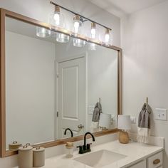 a bathroom with a large mirror and lights on the wall over the sink, along with other items