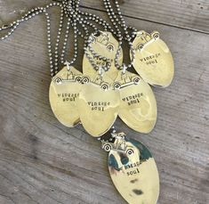 five yellow pendants with words on them are hanging from a chain that is attached to a wooden surface