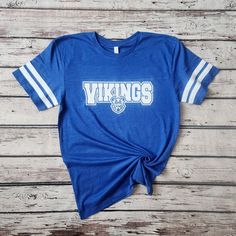 Introducing my Vikings school spirit lightweight jersey LAT tees, the perfect blend of softness, stretchiness, comfort, and cuteness! These tees are designed to elevate your school spirit wear to new levels of style and comfort. Crafted from high-quality lightweight material, these tees offer an exceptional softness that feels gentle against your skin. Embrace the comfort of these shirts, as they provide a cozy and luxurious feel that you'll never want to take off. The stretchy fabric ensures a Viking Mascot, Mascot Shirts, Spirit Wear Shirts, Spirit Wear Designs, Vikings Shirt, School Spirit Wear, Viking Shirt, School Spirit Shirts, Spirit Shirts