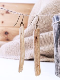 two pieces of wood hanging from a rope next to a cup