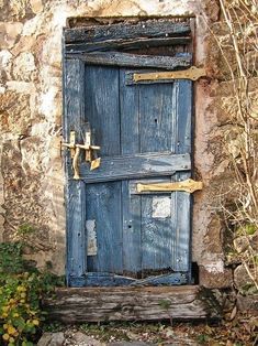 an old wooden door is open in front of a stone wall