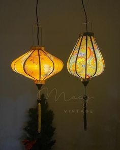 two lamps hanging from the ceiling in front of a christmas tree