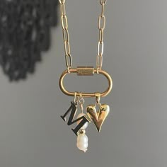 The Keepsake Necklace features a personalized initial charm and a convenient carabiner to easily add any other favorite charms you have. This necklace serves as a special container for all your cherished memories through charms. Featuring: Openable Carabiner with a Gold Plated Stainless Steel Initial Charm, a Long Pearly Charm, & our 18k gold plated Dainty Heart charm. The necklace is 16 inches long. Although this piece is made with water resistant materials, we always recommend to take pieces off before entering water!  while supplies last!  if you are a local customer, we can set up pickup/delivery and get your piece to you sooner!! Name Charm Necklace, Personalized Initial Necklace, Carabiner Necklace With Charms, Carabiner Charm Necklace, Popular Jewelry Trends 2024, Dainty Charm Necklace, Diy Charm Necklace, Charm Necklace Ideas, Personalized Jewelry For Mom