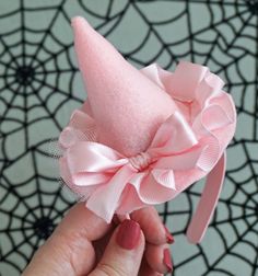 a hand holding a pink hat with a bow on it