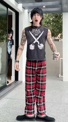 a man with black hair and tattoos wearing plaid pants